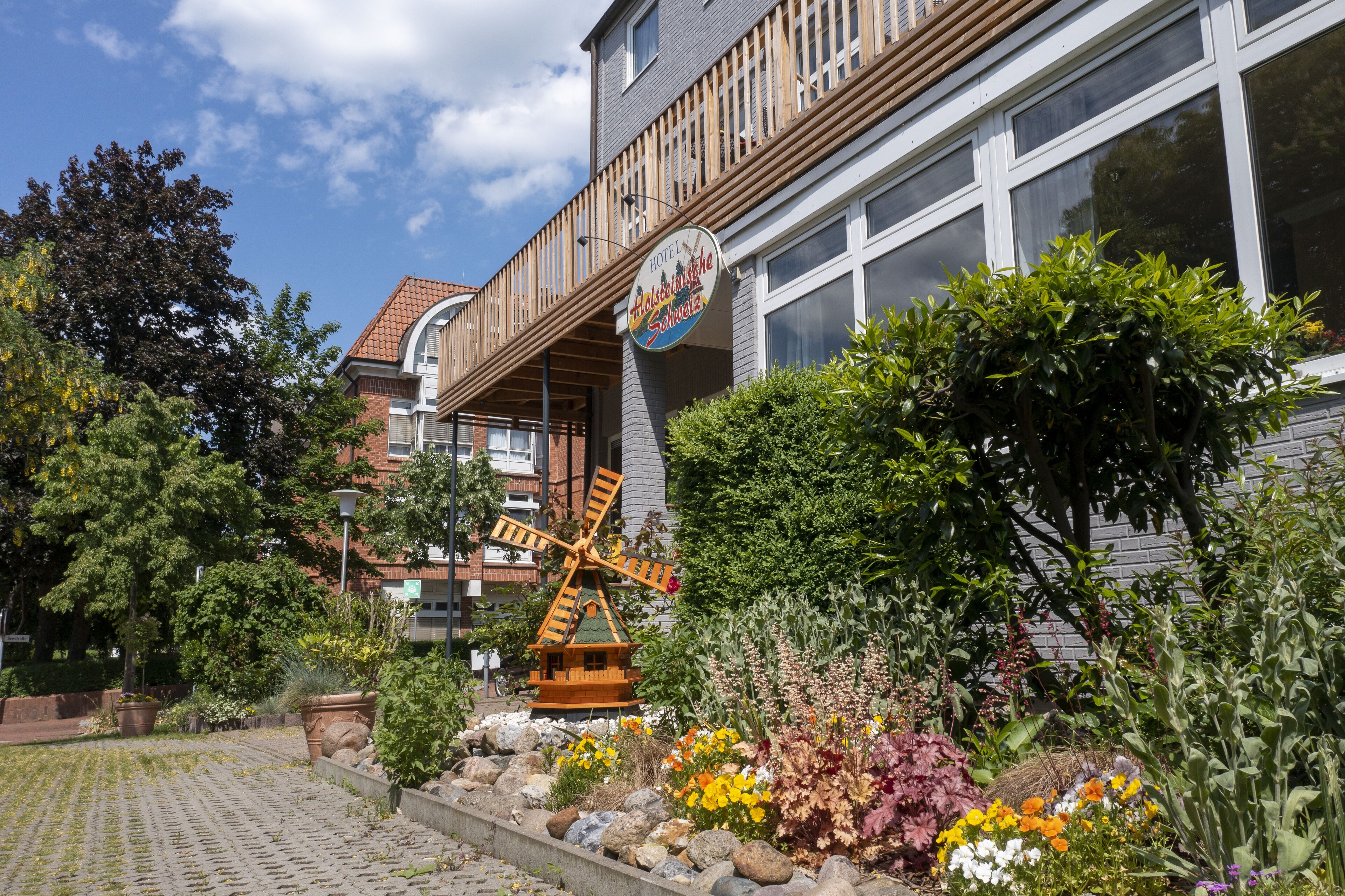 A hotel with a windmill, colorful flower beds, and a wooden deck.