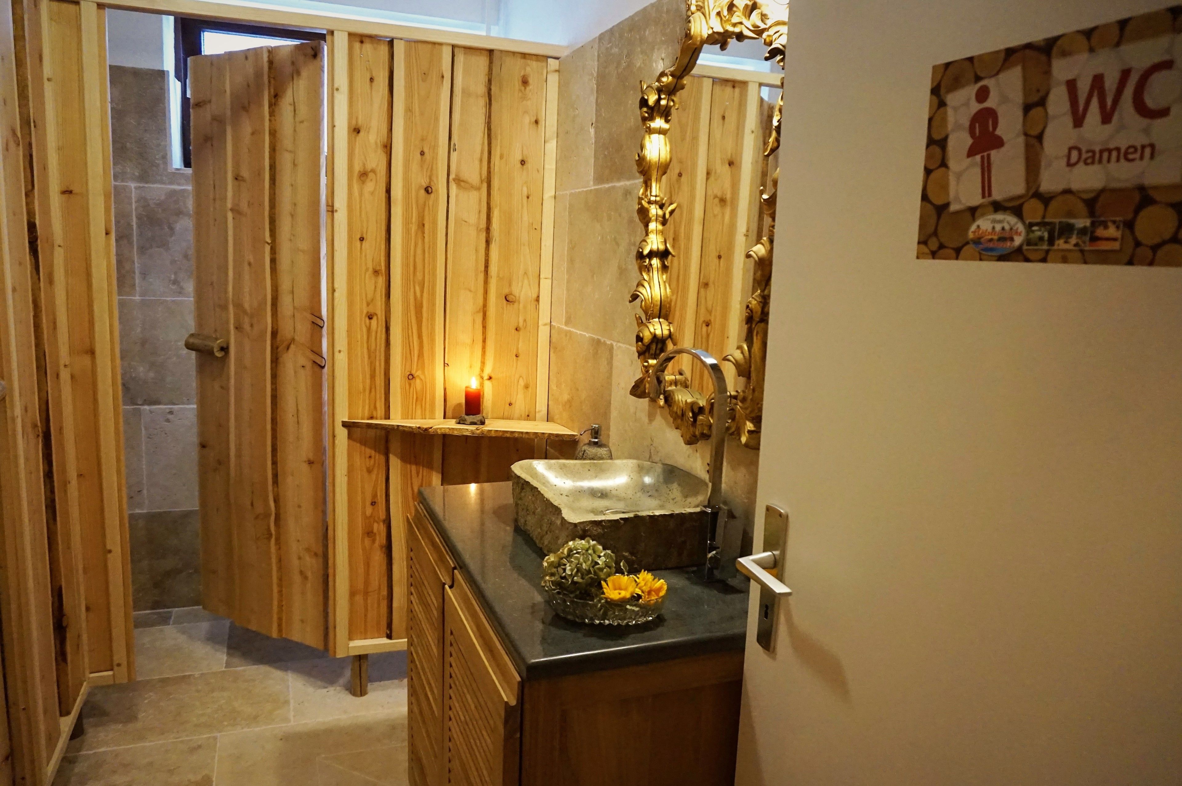 A wooden shower enclosure with a built-in sink and a mirror with an ornate frame.