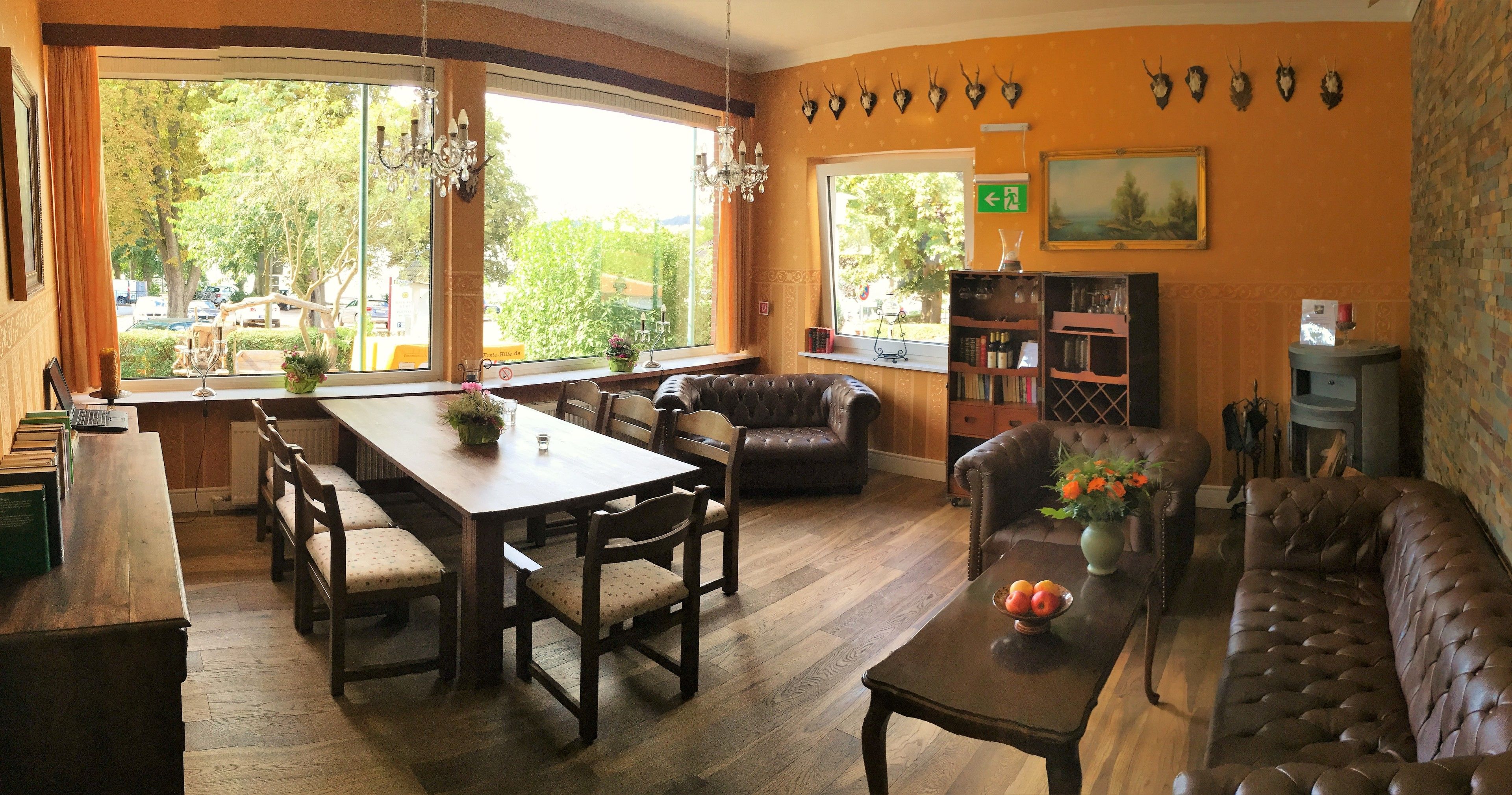 A cozy living room with a wooden dining table, leather sofas, and a bookshelf.