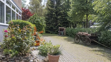 Stroll through a serene garden with lush greenery and a charming wooden cart.