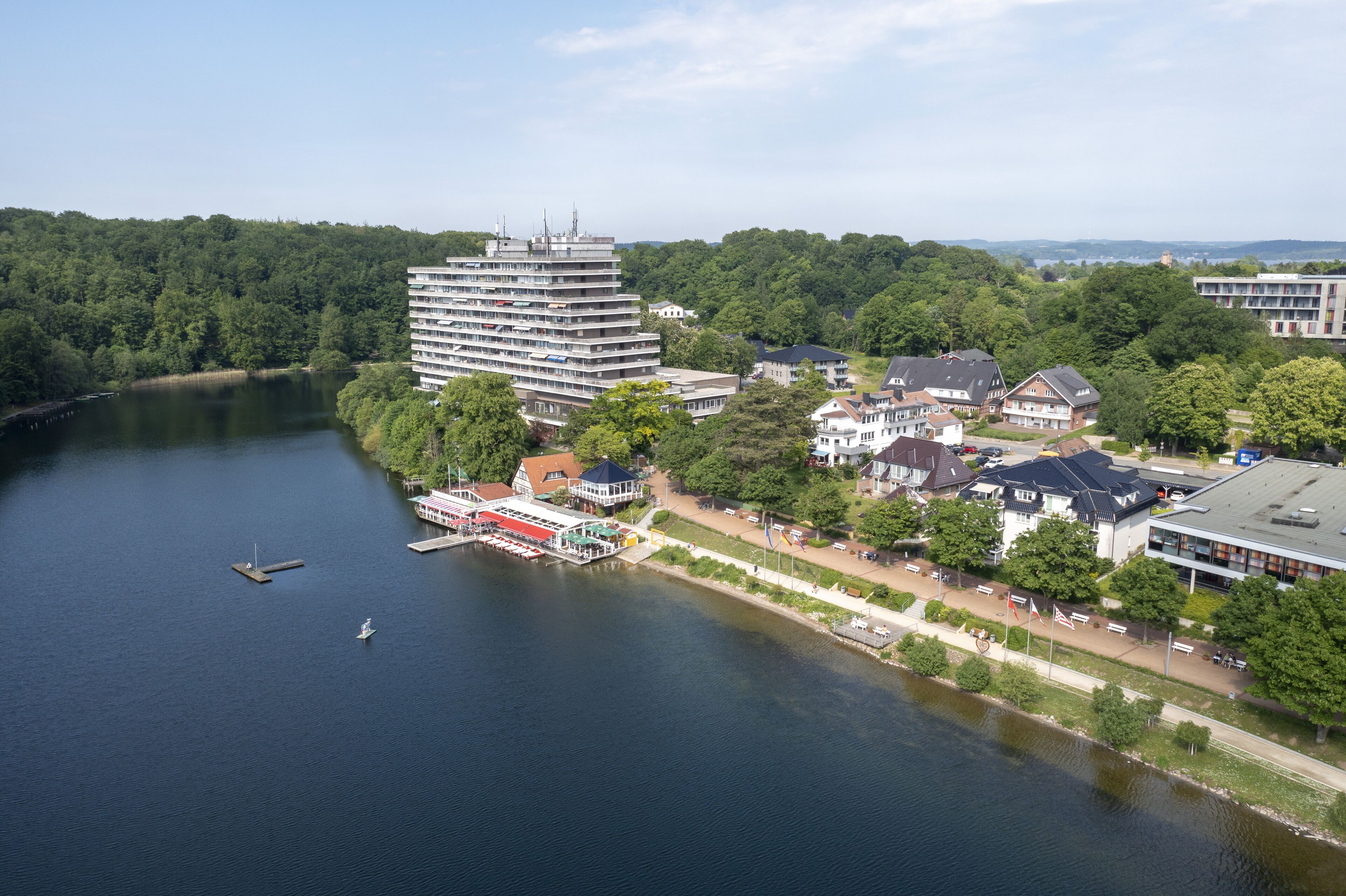 A riverside hotel with a large building, a dock, and a boat.