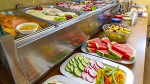 Un bufé con diversos alimentos, incluyendo salmón ahumado, queso, frutas y verduras.
