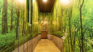 Un pasillo con un mural de un bosque en las paredes, piso de madera y una pequeña recepción al final.