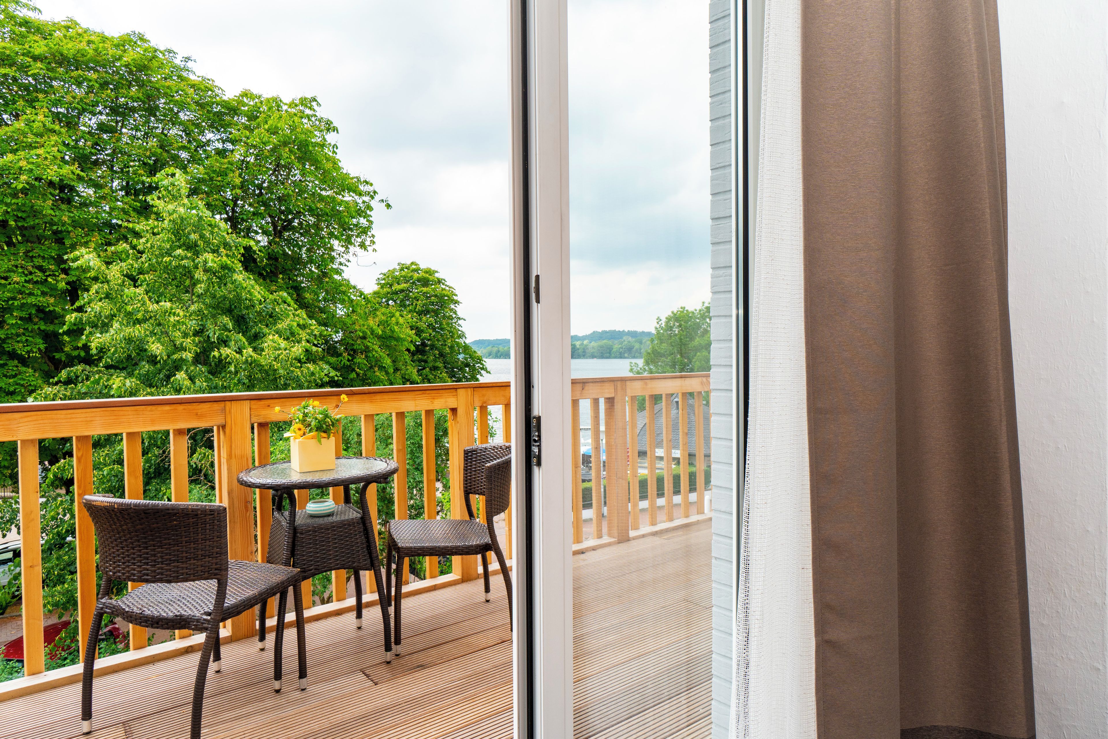 A balcony with a table and chairs, overlooking a green landscape.