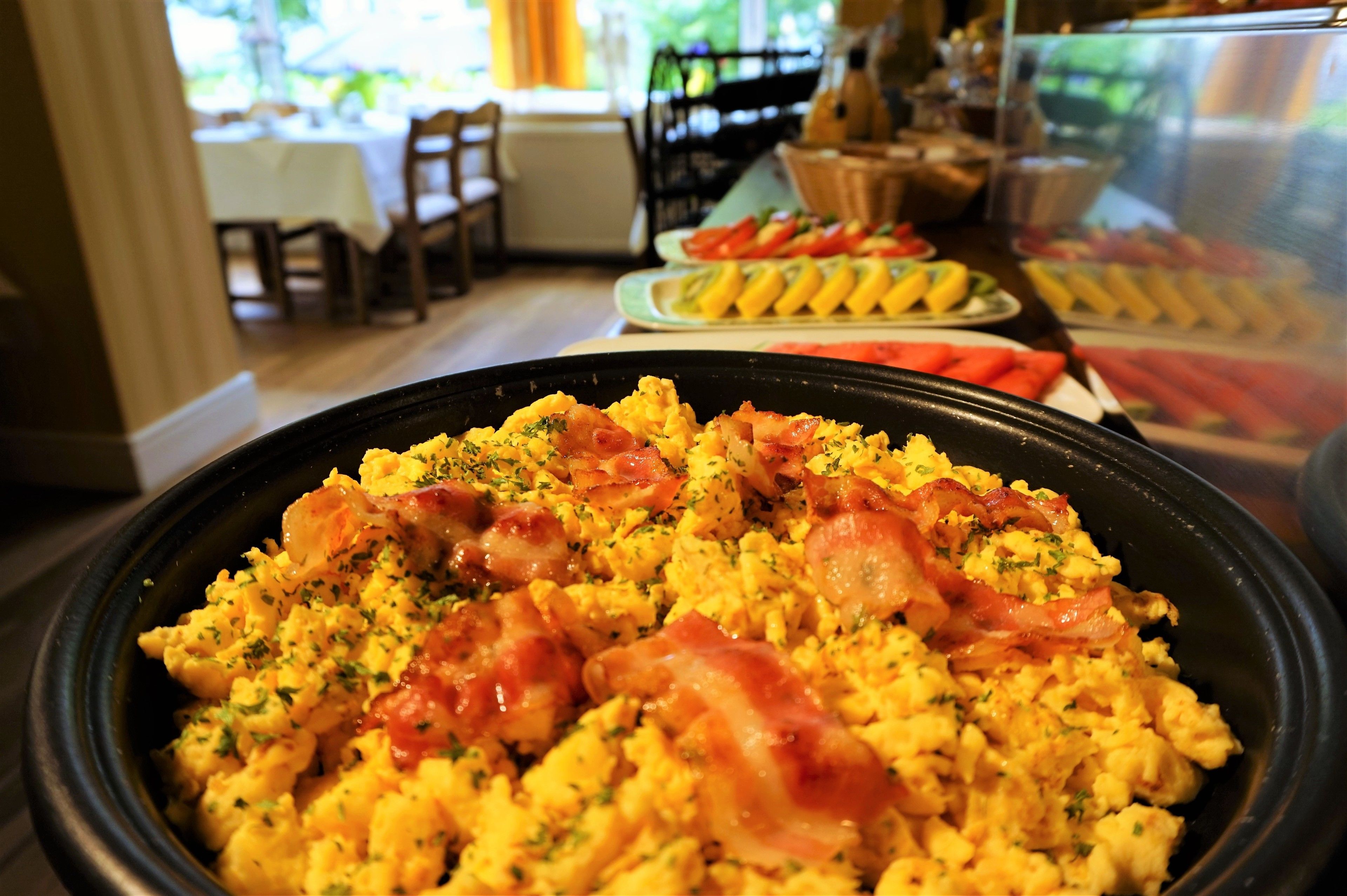 Un buffet de petit-déjeuner avec des œufs brouillés, du bacon et des herbes aromatiques.