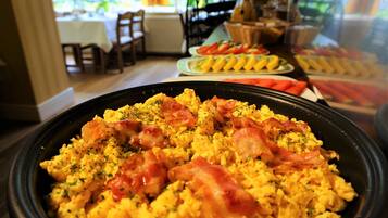 Un buffet de petit-déjeuner avec des œufs brouillés, du bacon et des herbes aromatiques.