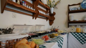 A buffet setup with various food items and beverages, wooden shelves with dishes, and a checkered tablecloth. - Hotel Xantener Eck (Berlin)