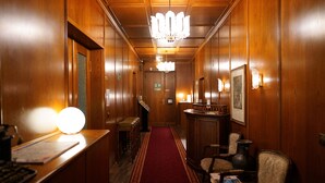 A hotel hallway with wooden paneling, a red carpet, a reception desk, and a chandelier. - Hotel Xantener Eck (Berlin)