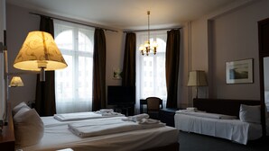 A hotel room with two beds, a desk, a chair, a television, and a chandelier. - Hotel Xantener Eck (Berlin)
