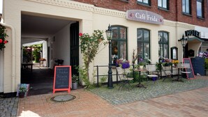 A café named 'Café Frida' with outdoor seating, a signboard, and a flower arrangement. - Hotel Cafe Frida (Bredstedt)