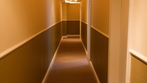 A long, narrow hallway with a carpeted floor and walls painted in a warm color. - Hotel Cafe Frida (Bredstedt)