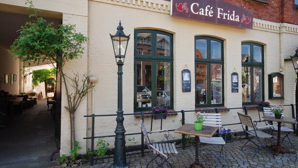 Café Frida with outdoor seating, a brick building, and a sign above the entrance. - Hotel Cafe Frida (Bredstedt)