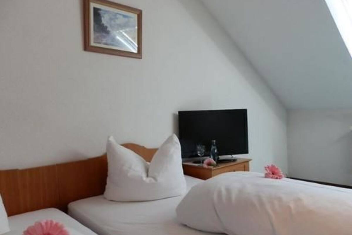A hotel room with a bed, a television on a wooden nightstand, and a framed picture on the wall.
