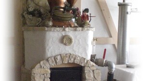 Una chimenea de piedra con una chimada, un jarron decorativo y una pequeña estatua encima.