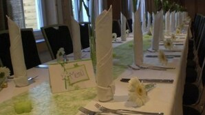 Una mesa de banquete dispuesta con manteles blancos, servilletas y cubiertos.