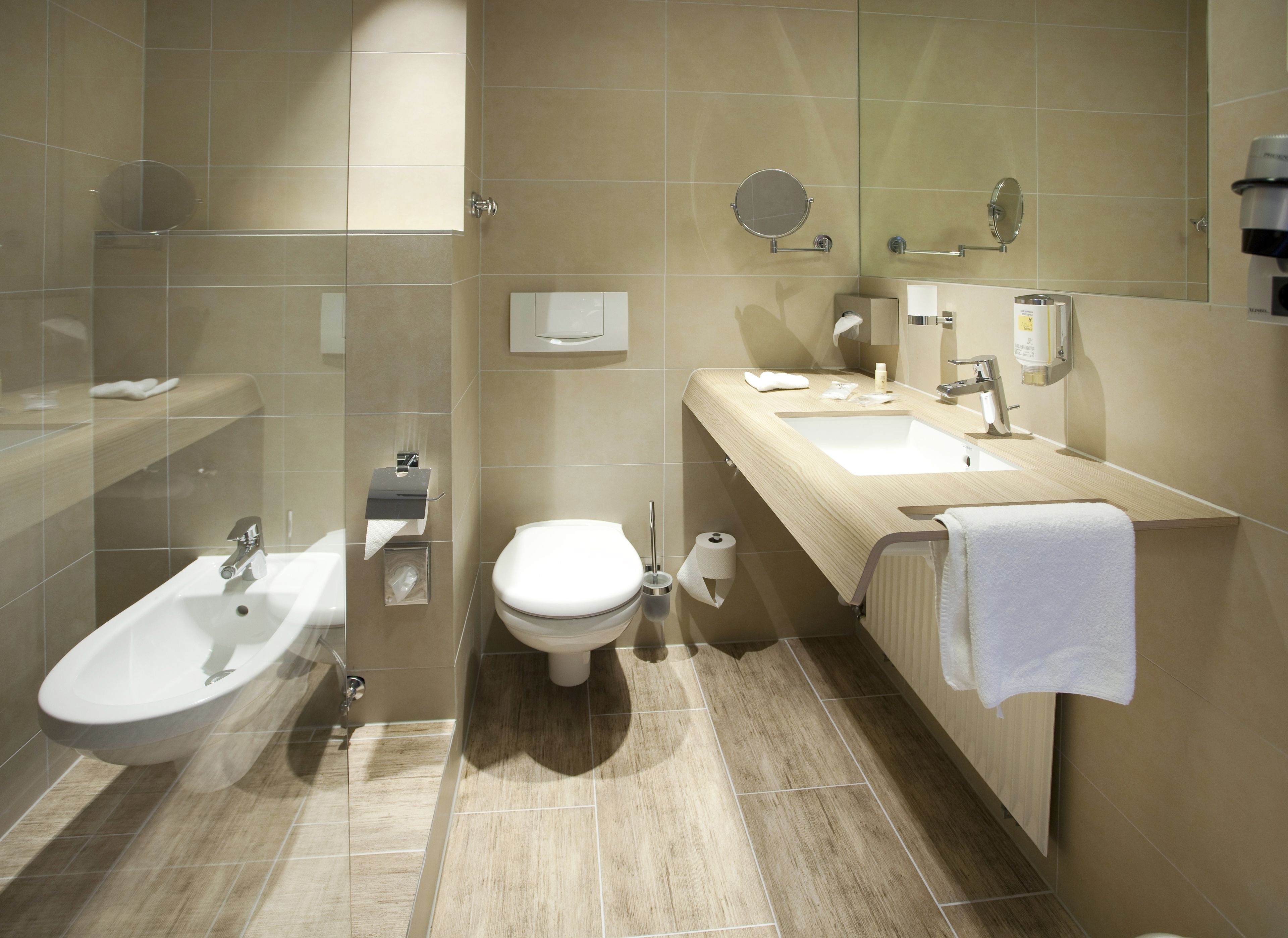 Ein modernes Badezimmer mit integriertem Bidet, Toilette, Waschbecken und Spiegel.