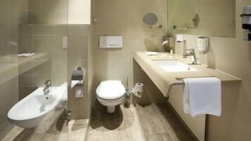 Ein modernes Badezimmer mit integriertem Bidet, Toilette, Waschbecken und Spiegel.