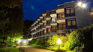 Un hotel de varios pisos con balcones, un camino pavimentado y zonas bien iluminadas.