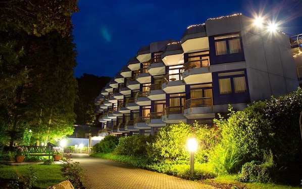 Un hotel de varios pisos con balcones, un camino pavimentado y zonas bien iluminadas.