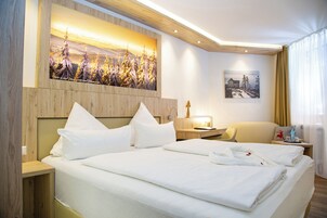 Habitación de hotel con una cama grande, una mesita de noche, una silla y un cuadro en la pared.
