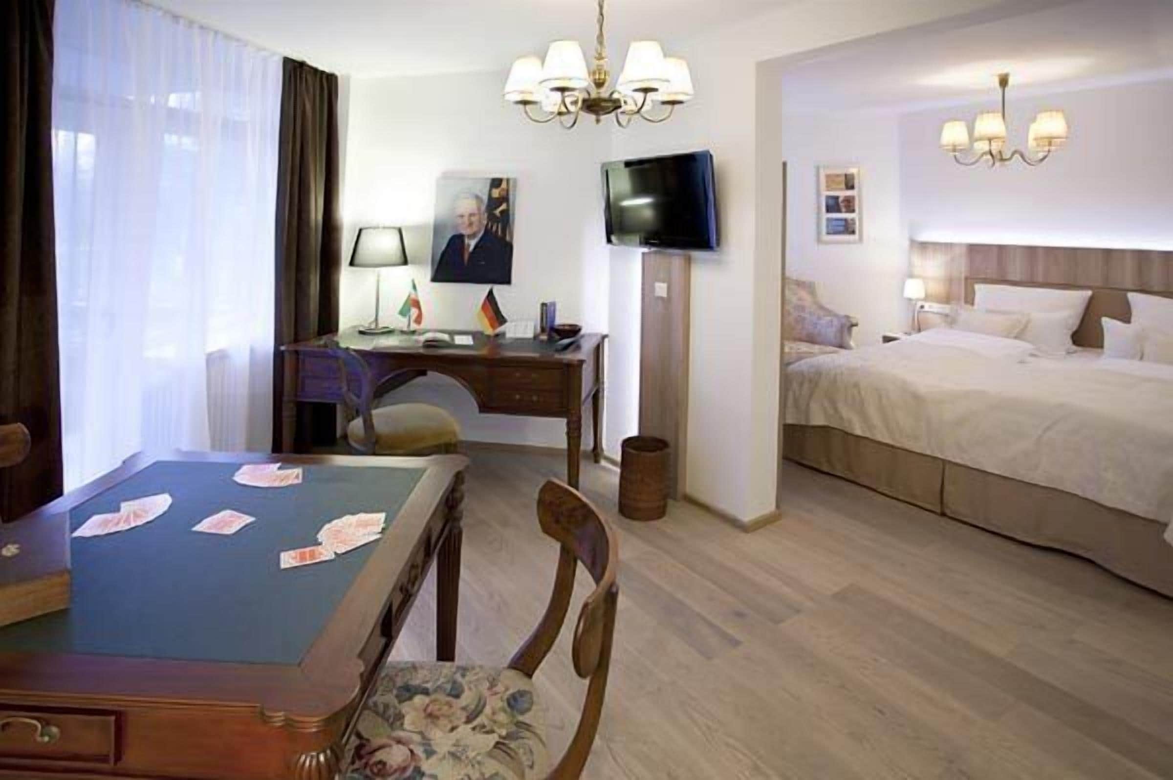 Ein Hotelzimmer mit einem Bett, einem Schreibtisch mit Stuhl, einem Fernseher und einem Tisch mit Spielkarten.