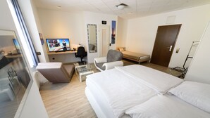 A hotel room with a large bed, a desk with a computer, a chair, a TV, and a mirror. - Hotel Boeving (Breckerfeld)