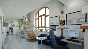 A modern office with a staircase, a computer desk, and blue chairs. - Hotel Boeving (Breckerfeld)
