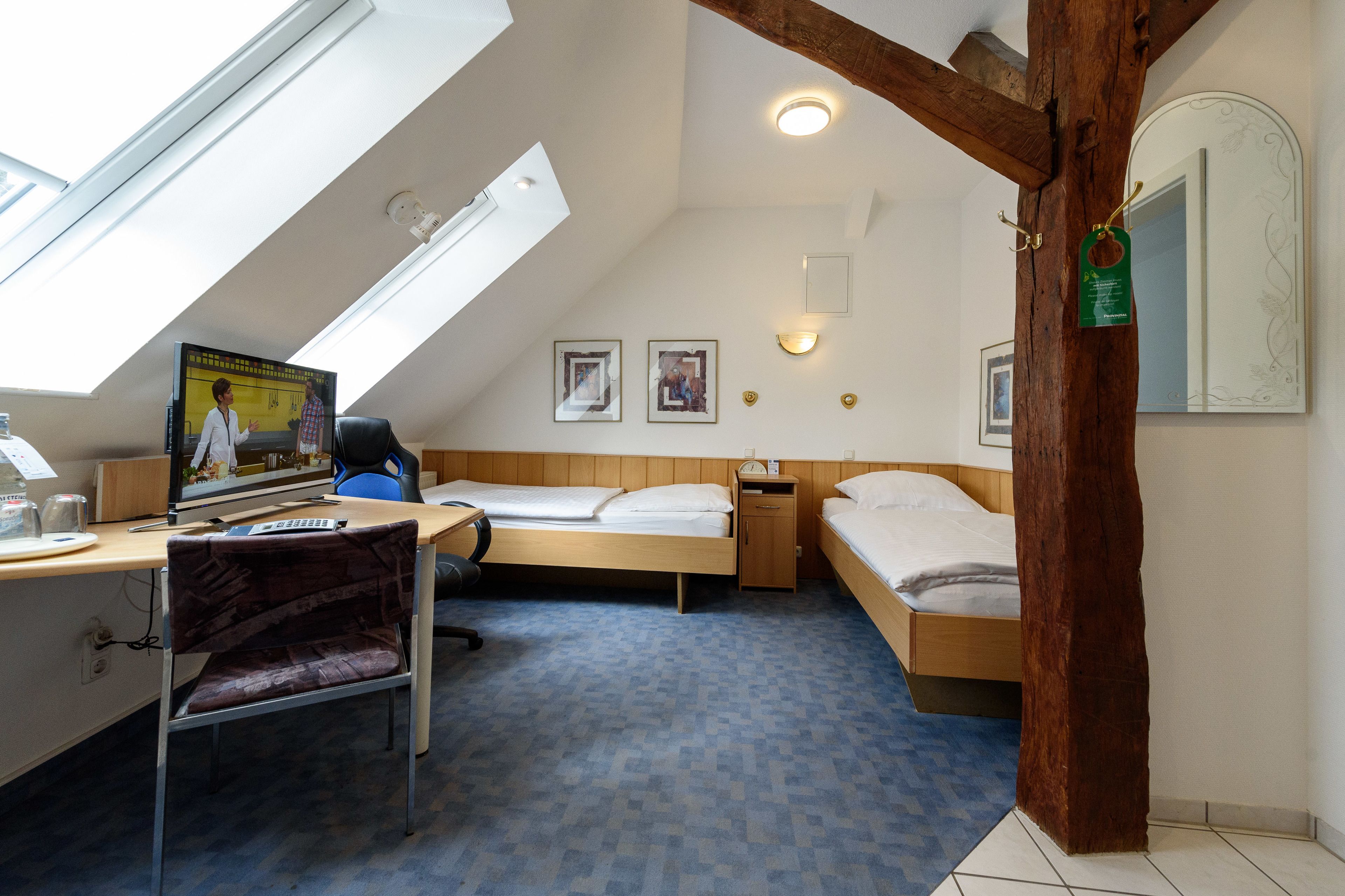 A room with a bed, desk, chair, and a large window.