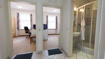 Quarto de hotel com chuveiro, escrivaninha e cadeira.