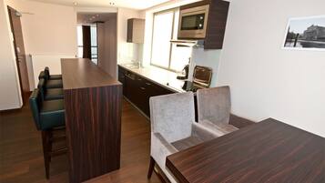 Una cocina moderna con armarios de madera oscura, un microondas integrado y un amplio ventanal.