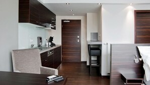 A compact hotel room with a kitchenette, a bed, a desk, and a chair. - Boardinghouse Bielefeld (Bielefeld)