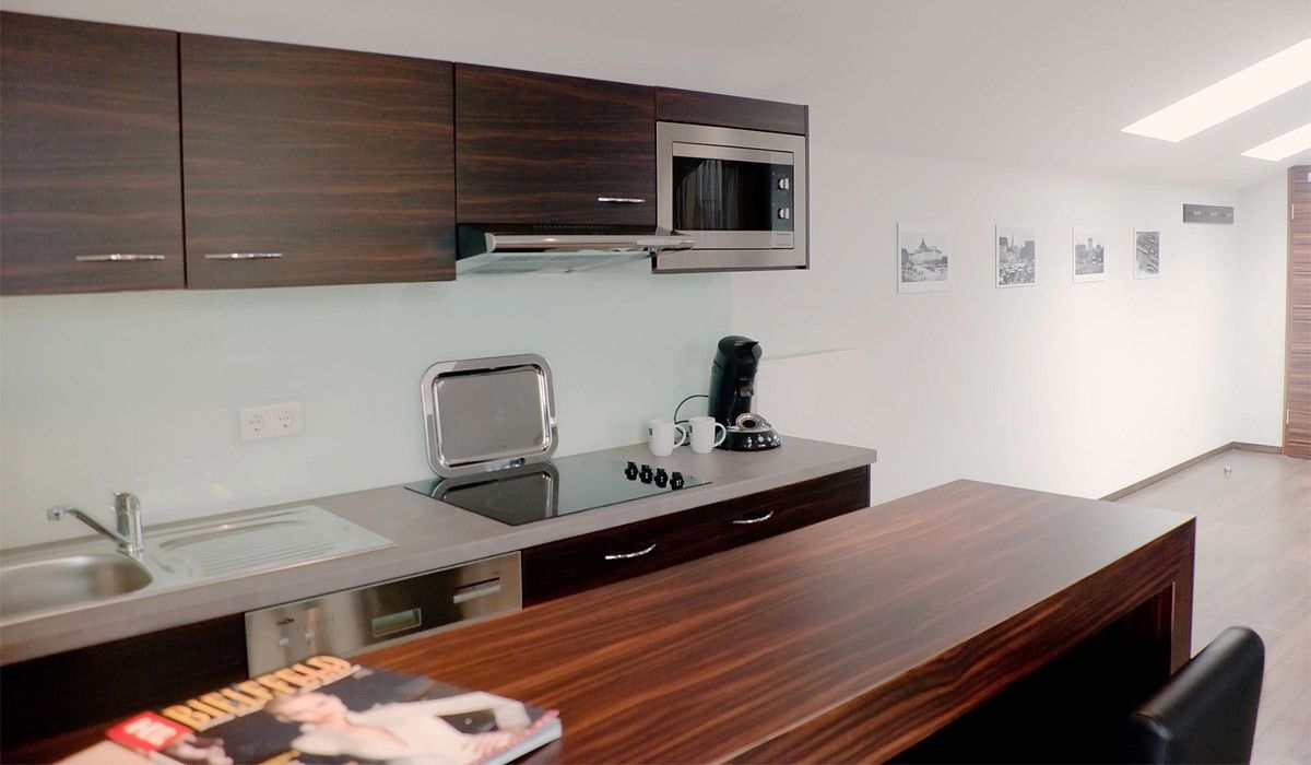 Une cuisine moderne avec des meubles de rangement en bois foncé, des appareils électroménagers en acier inoxydable et une table à manger en bois.