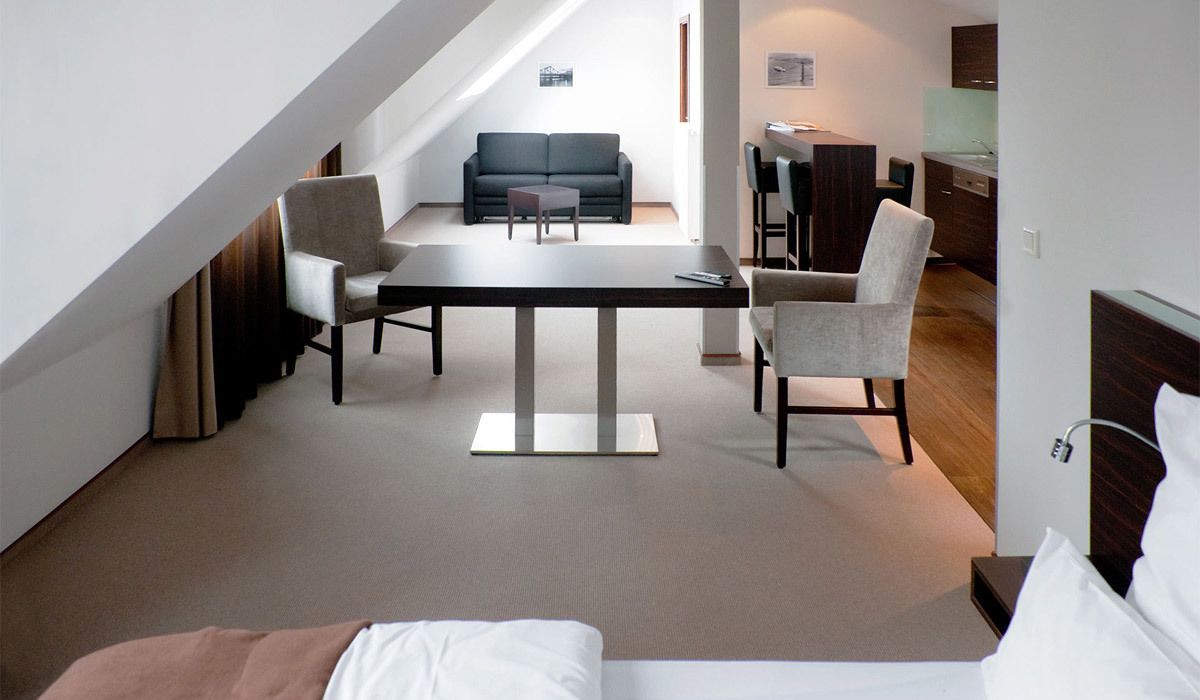 Moderni hotellihuone, jossa on sänky, ruokapöytä ja sohva.