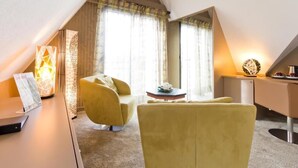 Una habitación moderna y bien iluminada con un sillón amarillo, un escritorio y un espejo grande.