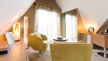 A room with a desk, two yellow chairs, a small table, and a mirror.