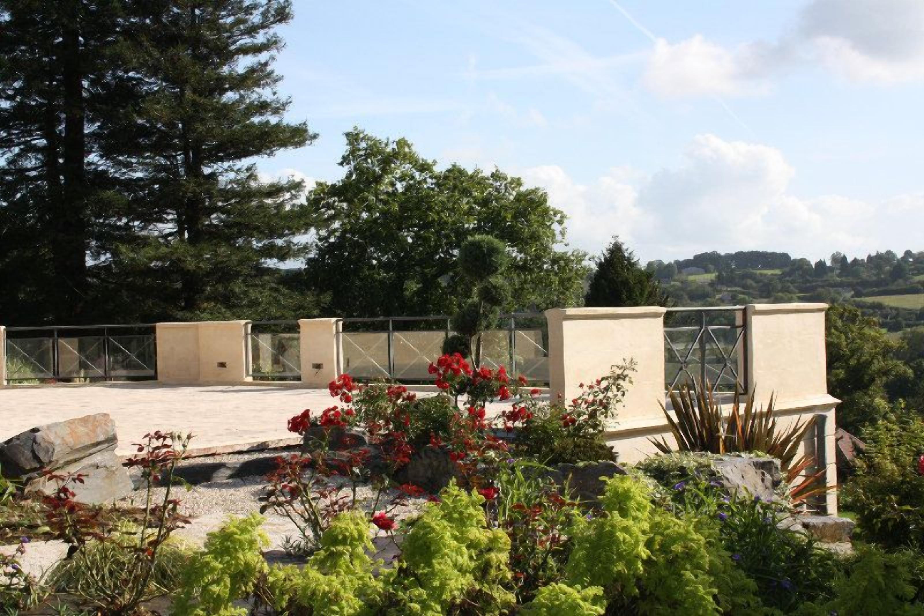 A rooftop terrace with a view of the countryside, a pergola, and a variety of plants.