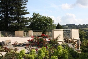 Una terraza en la azotea con vistas al campo, una pérgola y diversas plantas.