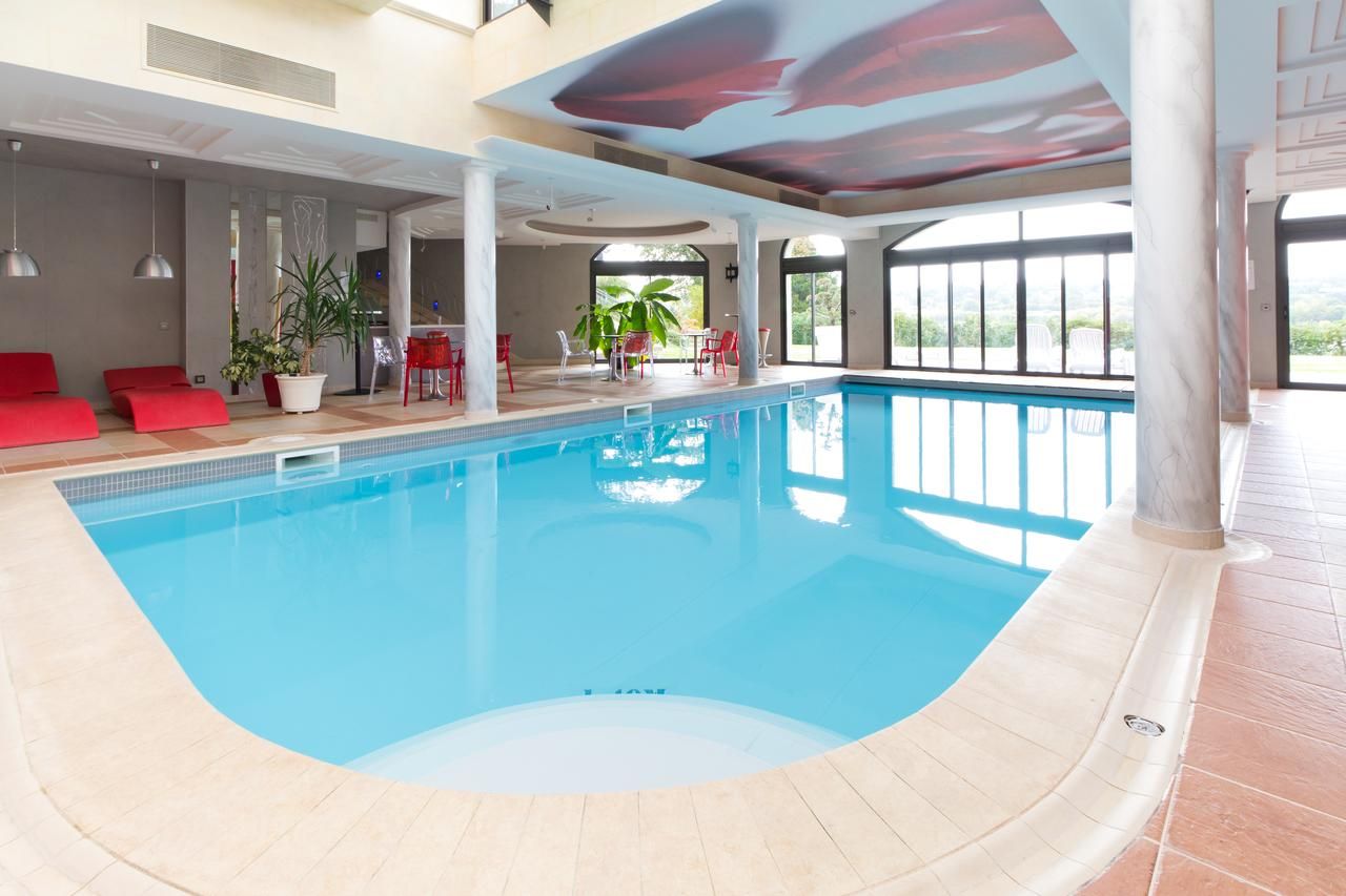 An indoor swimming pool with a clear view of the surrounding area, including seating and plants.