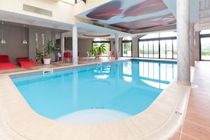 Piscina interior con vistas despejadas del entorno circundante, que incluye asientos y plantas.