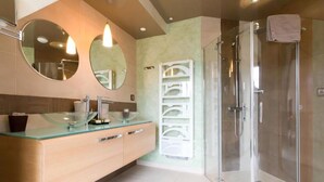 A modern bathroom with a glass shower enclosure, a beige vanity with a glass bowl sink, and two round mirrors. - Le Domaine Des Chevaliers De Malte Hotel (Villedieu-les-Poêles-Rouffigny)