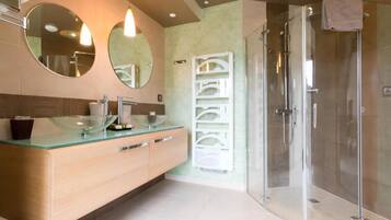 A modern bathroom with a glass-enclosed shower, a glass-topped vanity, and two wall-mounted mirrors.