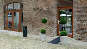 A brick building with a sign reading "RESTAURANT" above the entrance. There are two potted plants in front of the doors.