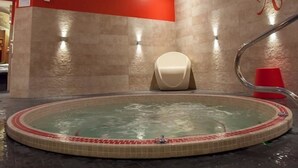 A spa room with a hot tub, a red accent wall, and a skylight. - Hotel & Spa Le Bouclier D'Or (Strasbourg)