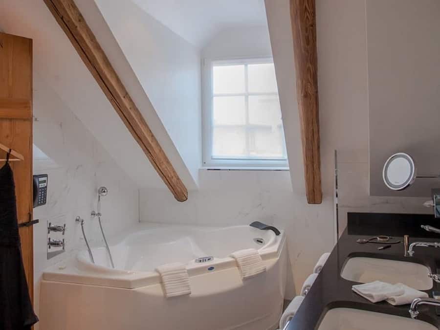 A modern bathroom with a freestanding bathtub, a vanity with a mirror, and a window providing natural light.