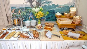 A buffet table with various food items and a painting of a landscape in the background. - Hotel & Spa Le Bouclier D'Or (Strasbourg)