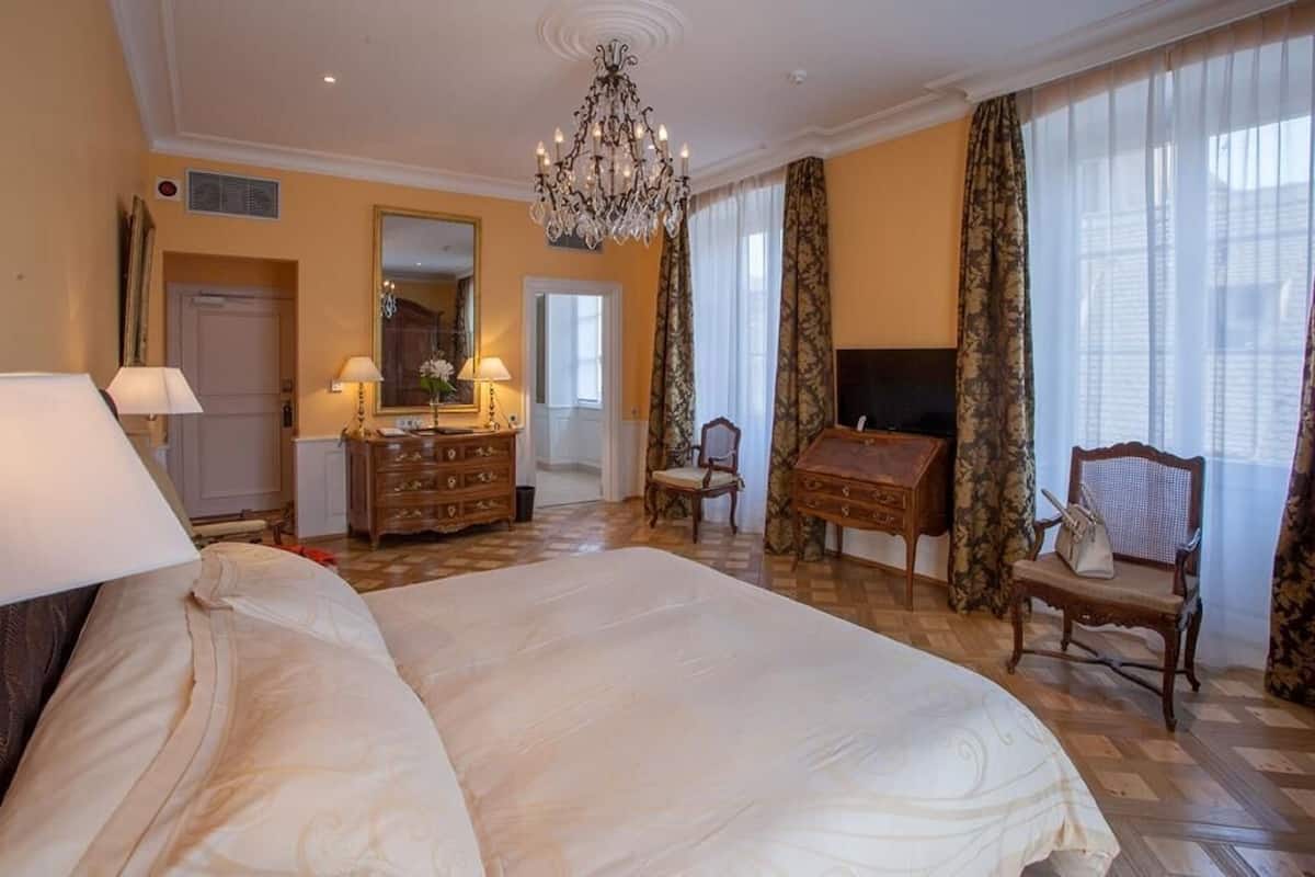 Quarto de hotel espaçoso com uma cama grande, penteadeira de madeira, escrivaninha e uma cadeira.