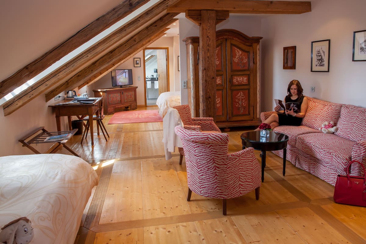 Um quarto acolhedor com teto de madeira, um sofá, uma poltrona, uma mesa e um armário.