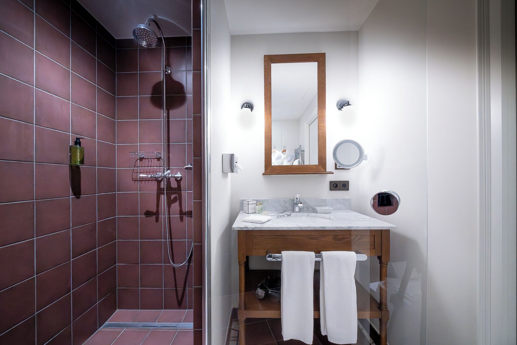 A bathroom with a shower, a sink, a mirror, and a towel rack.