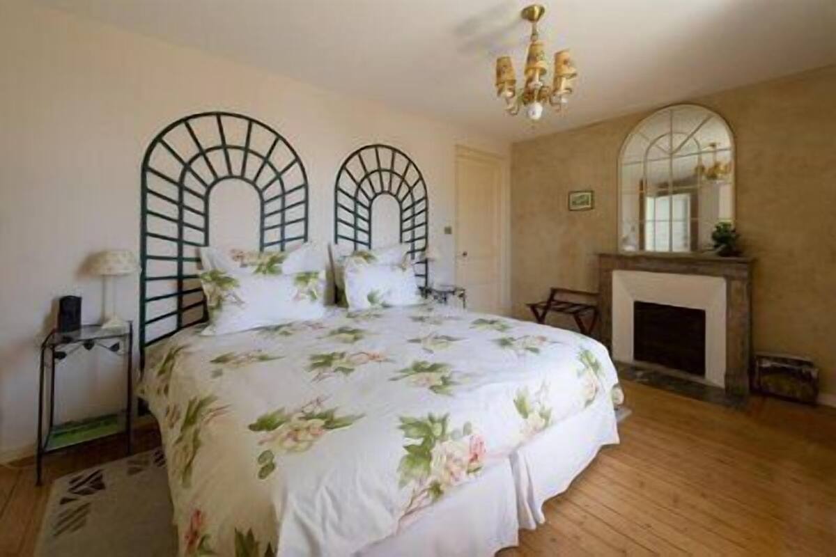 Quarto com cama grande, lareira e espelho na parede.