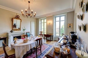 A dining area with a chandelier, a fireplace, and a table set for a meal.